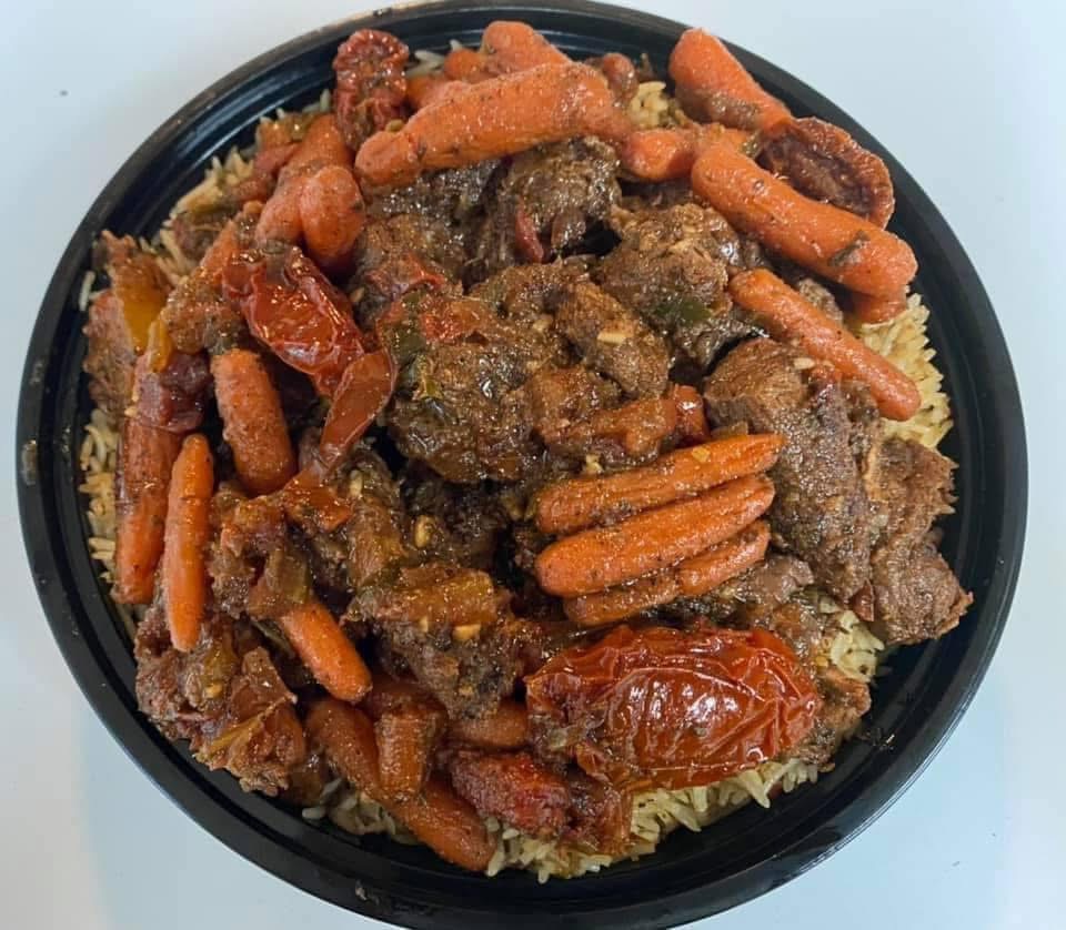 Smothered beef tips with carrots over rice in a catering pan